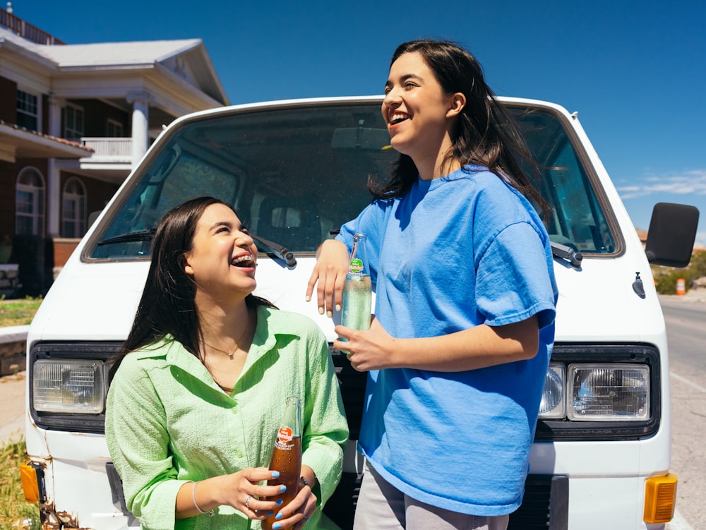 a couple of women standing next to a white van