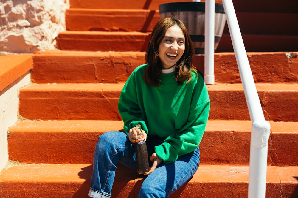 a woman in a green sweater sitting on some steps