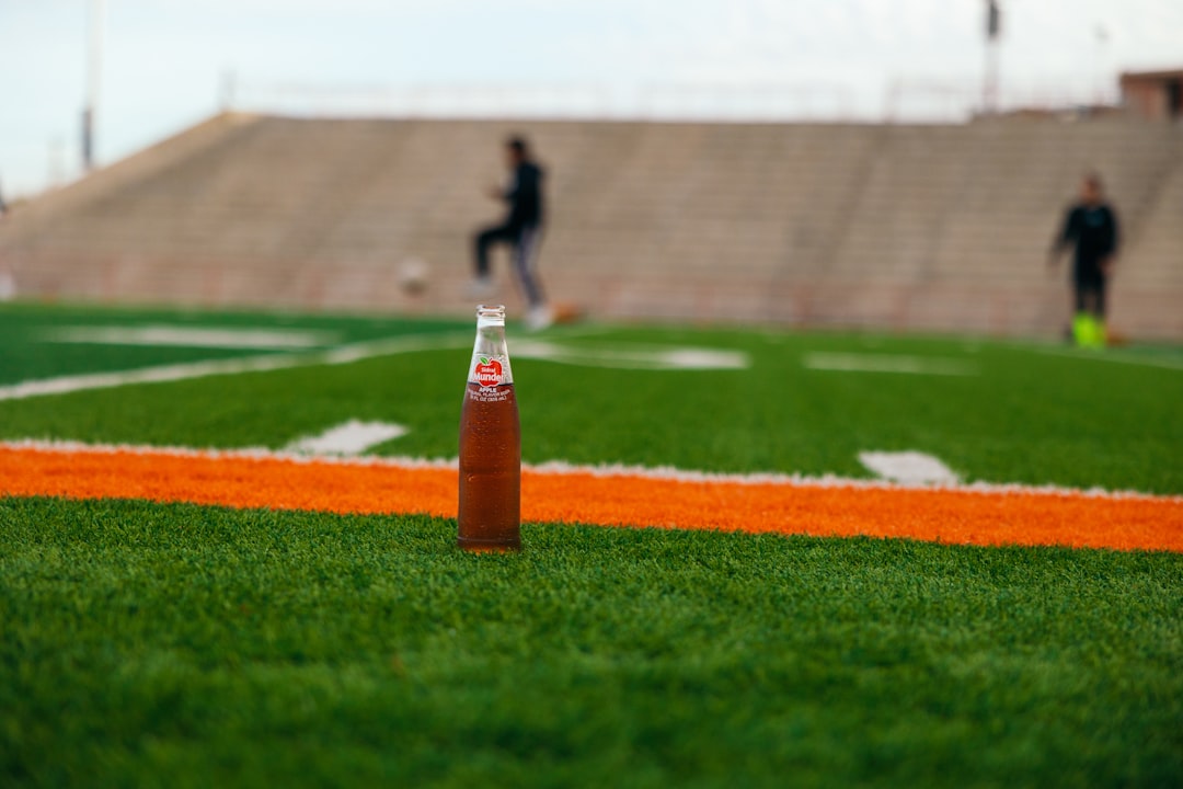 a bottle of soda sitting on top of a green field,