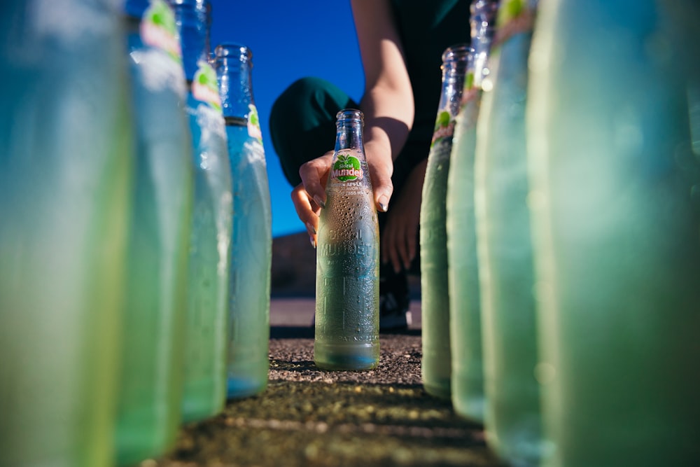 a person kneeling down next to a bunch of bottles