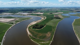 Aerial view of vast Brazilian farmland with green fields and a winding river under a clear sky.