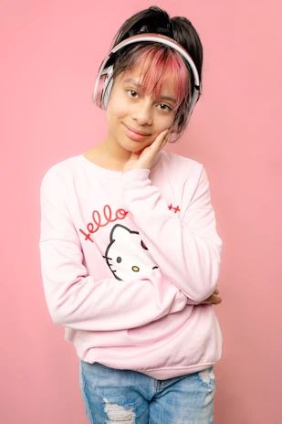 Fionaledieuhien smiling warmly while wearing pink headphones in a softly lit home studio.