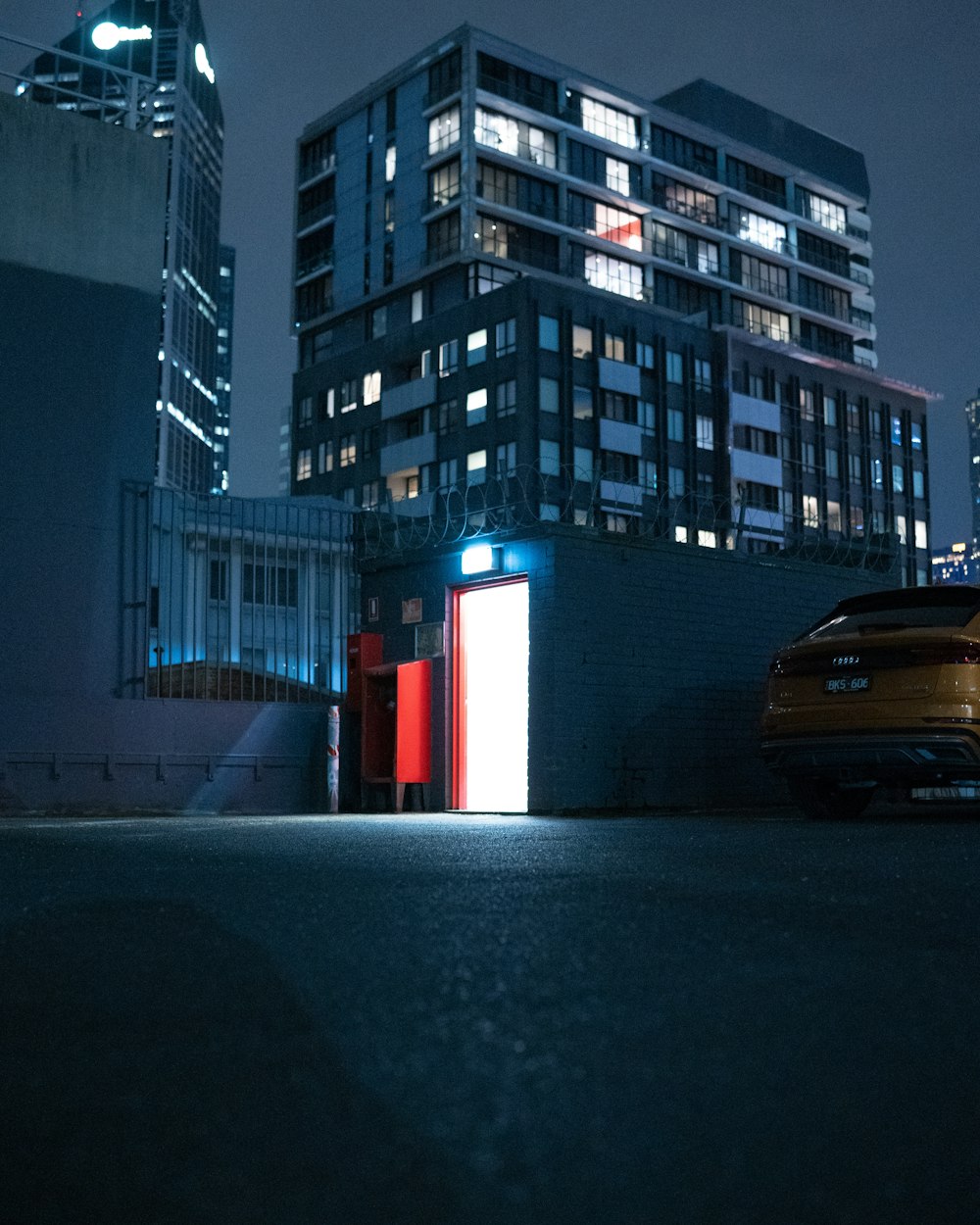 a car parked in front of a tall building at night
