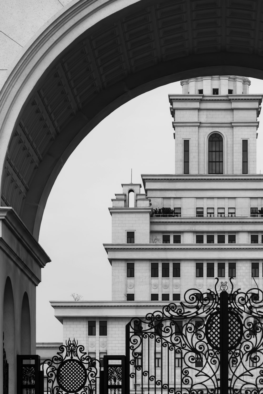 a black and white photo of a gate and a building
