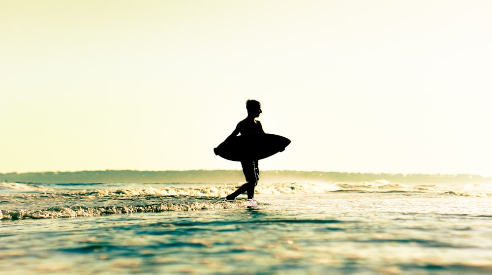 una persona in piedi in acqua con una tavola da surf