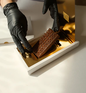 A delivery person handing over a beautifully wrapped box of chocolates in a cozy home setting.