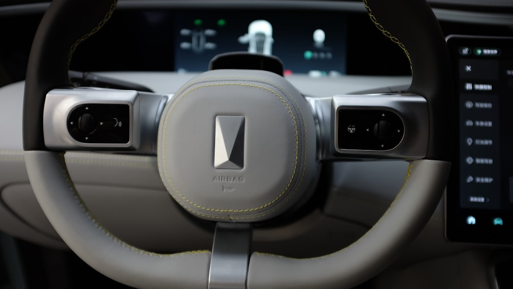 the steering wheel of a car with a display in the background