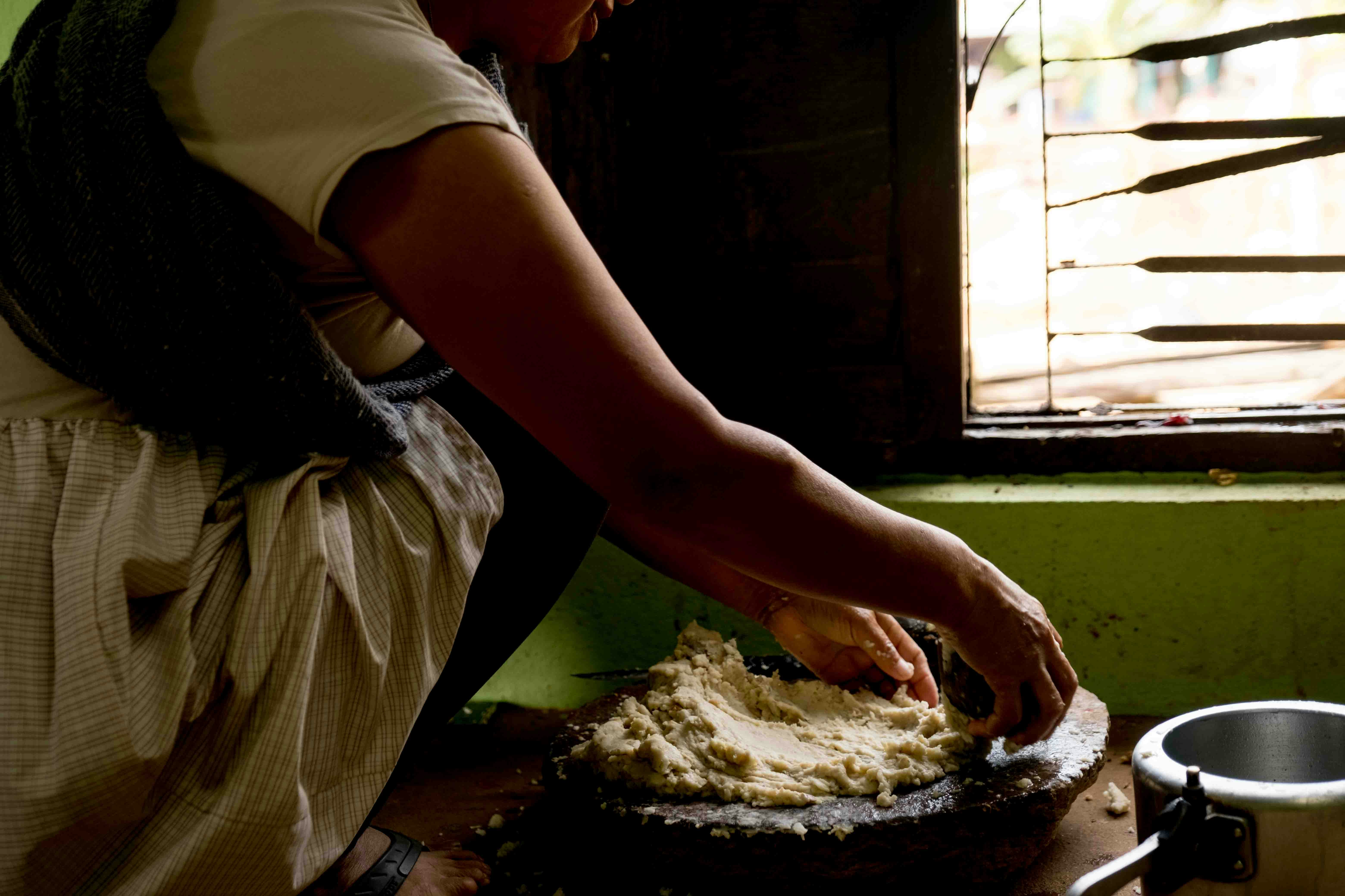a woman in an apron is kneading dough