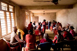 Community elders sharing stories in a warmly lit cultural hall.