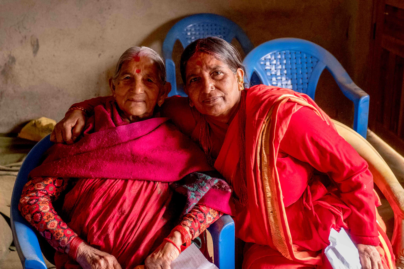 An adult daughter sitting close to her aging mother at home, the kind of calm conversation that's the right setting for building an emergency information sheet