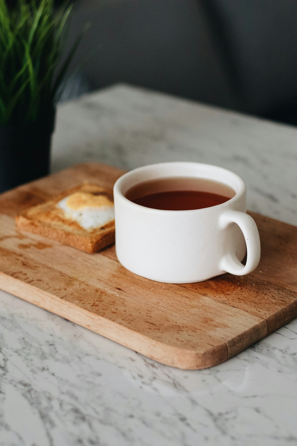 a cup of tea and a piece of bread on a cutting board