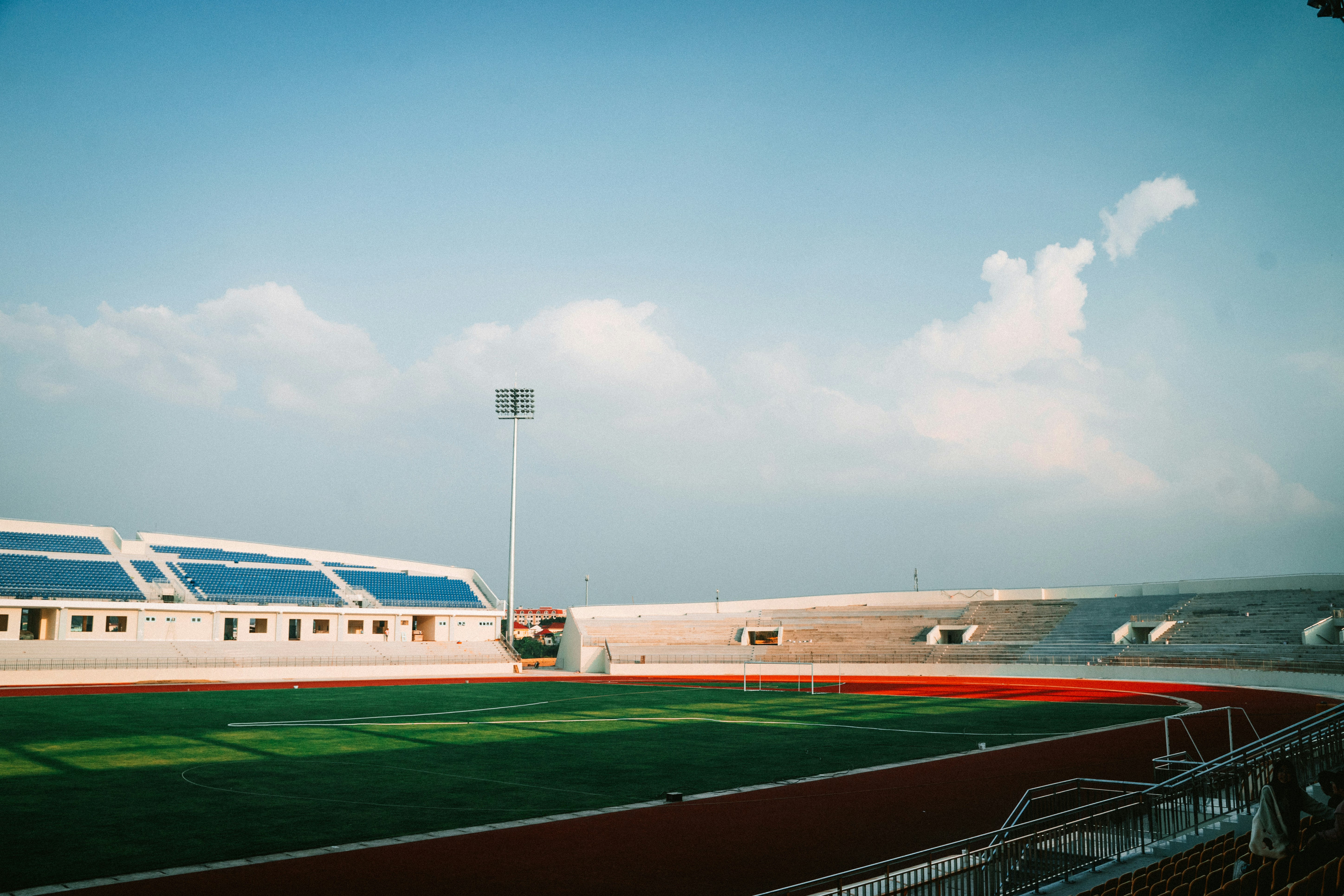 stadion dengan lapangan hijau dan langit biru