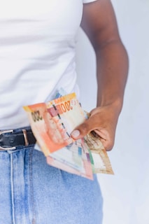a person holding a bunch of money in their pocket