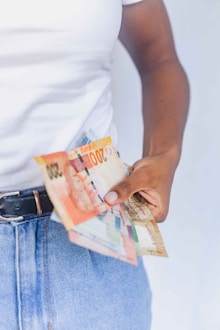 a person holding a bunch of money in their pocket