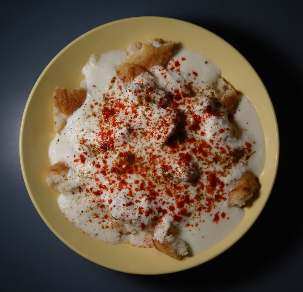 une assiette jaune surmontée de nourriture sur le dessus d’une table