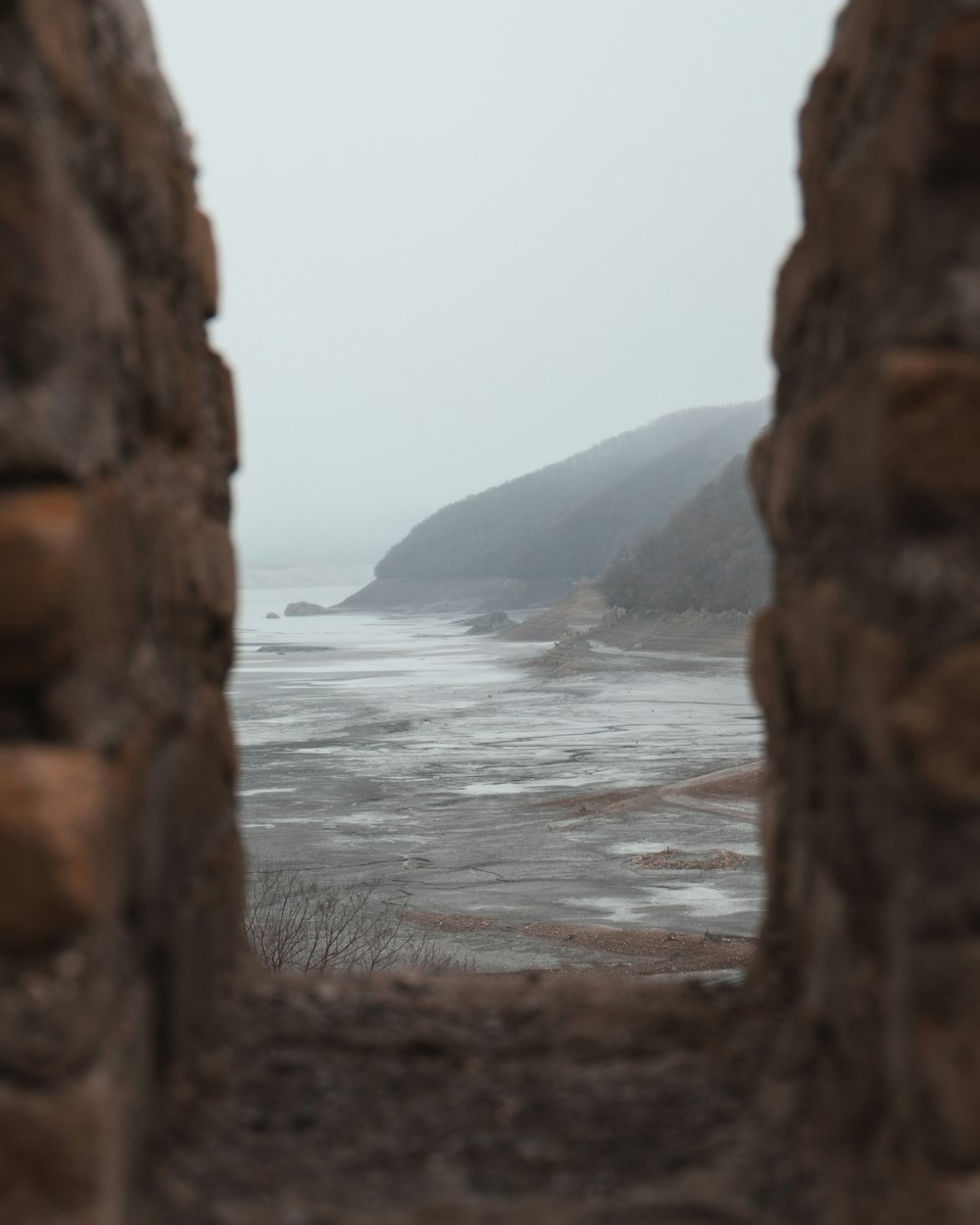 a view of a body of water through a stone wall