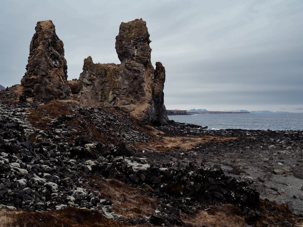 a rock formation on a rocky beach with a body of water in the background