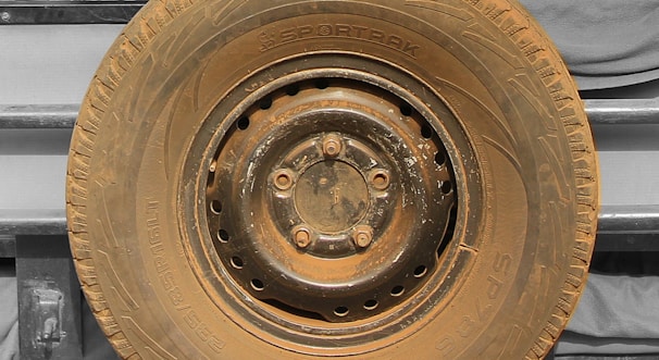 Close-up of a worn truck tire with visible tread patterns in a yellow and black themed workshop.