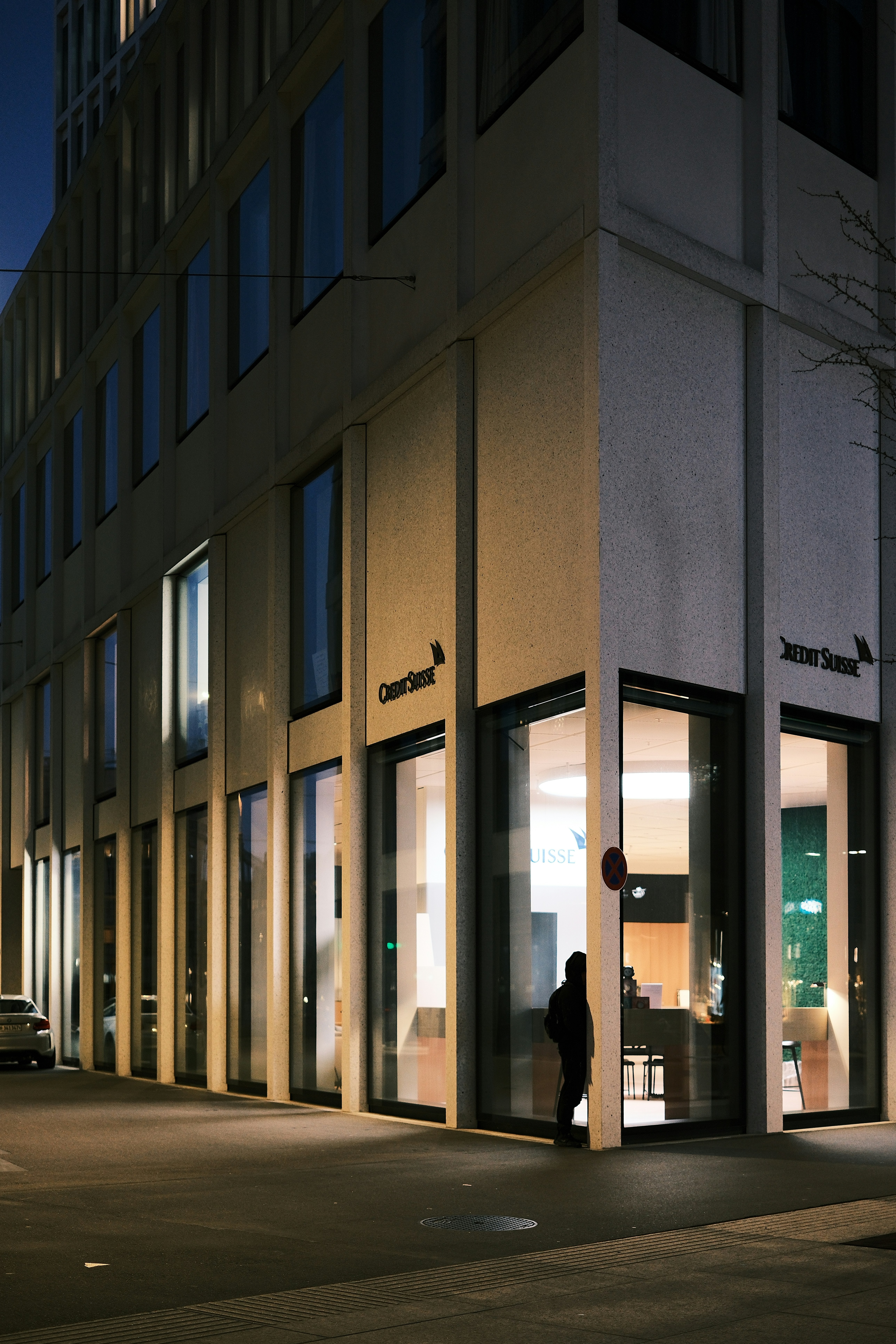 A vigilant security guard monitoring a modern office building at dusk.