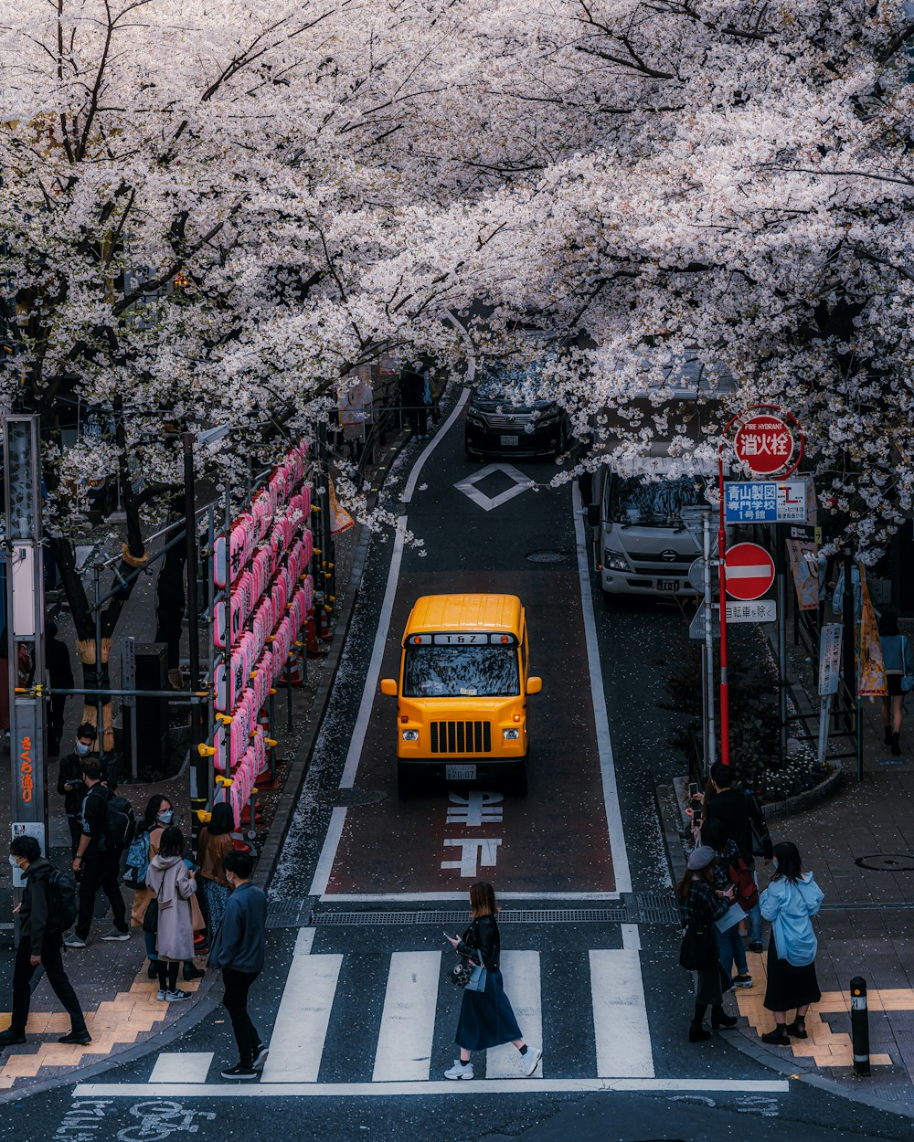 a yellow bus driving down a street next to a crowd of people