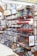 The image features a well-stocked store shelf filled with a variety of colorful ceramic and pottery items. There are numerous bowls, plates, and vases, most displaying intricate patterns and vibrant colors such as blue, red, and green. Decorative lanterns and framed artwork are also visible, along with small ceramic fruit ornaments.