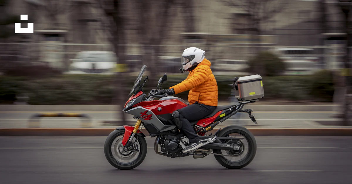 A man riding a red motorcycle down a street photo – Free Image on Unsplash