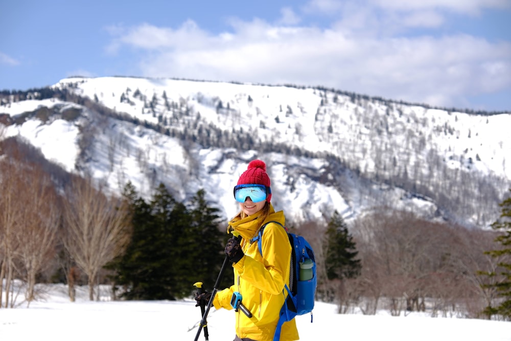 a person in a yellow jacket and a blue backpack on skis