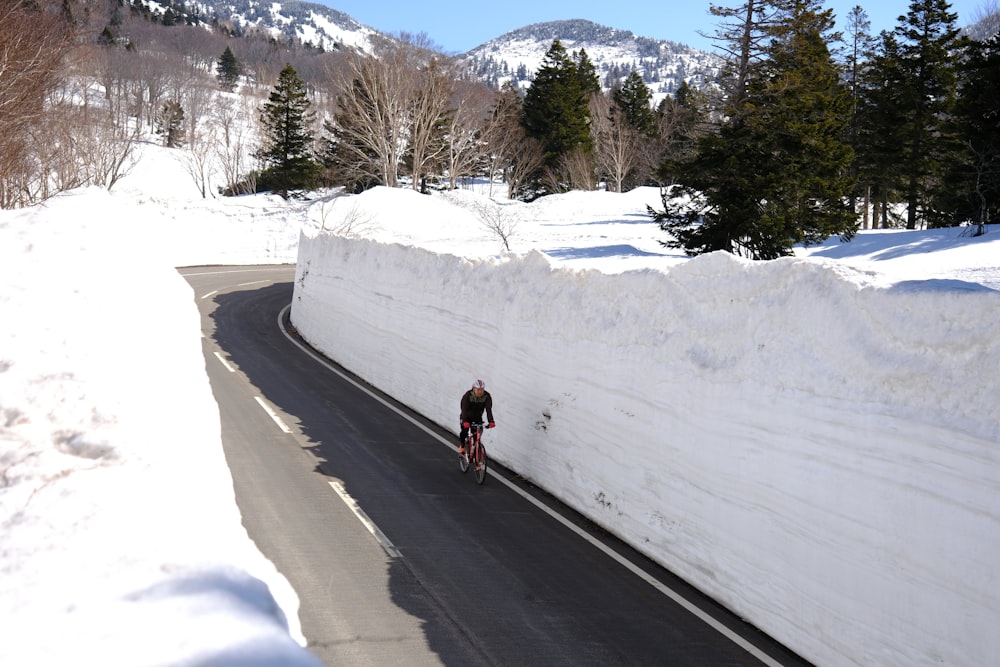 Ein Mann, der mit dem Fahrrad eine schneebedeckte Straße hinunterfährt