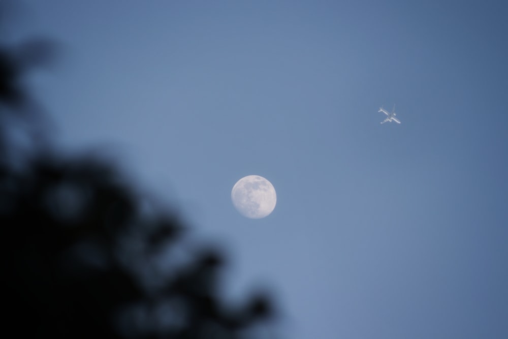 a plane flying in the sky with the moon in the background