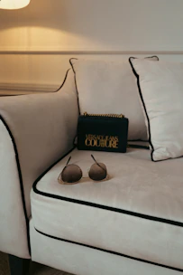 Close-up of a luxurious black leather tote bag resting on a plush leather sofa beside a decorative vase.
