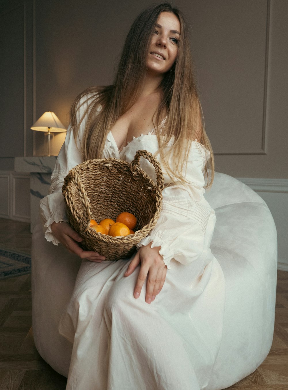 a woman in a white dress holding a basket of fruit