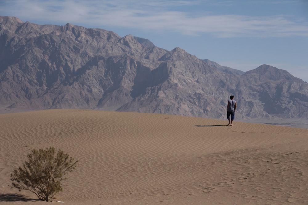 Un homme debout au sommet d’une colline de sable