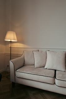 a white couch sitting in a living room next to a lamp