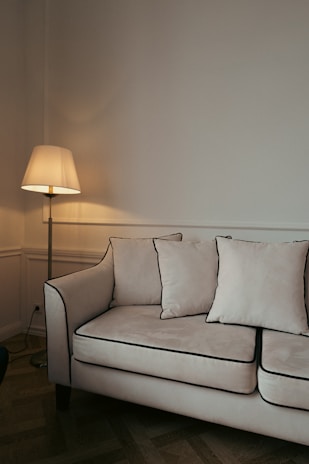 a white couch sitting in a living room next to a lamp