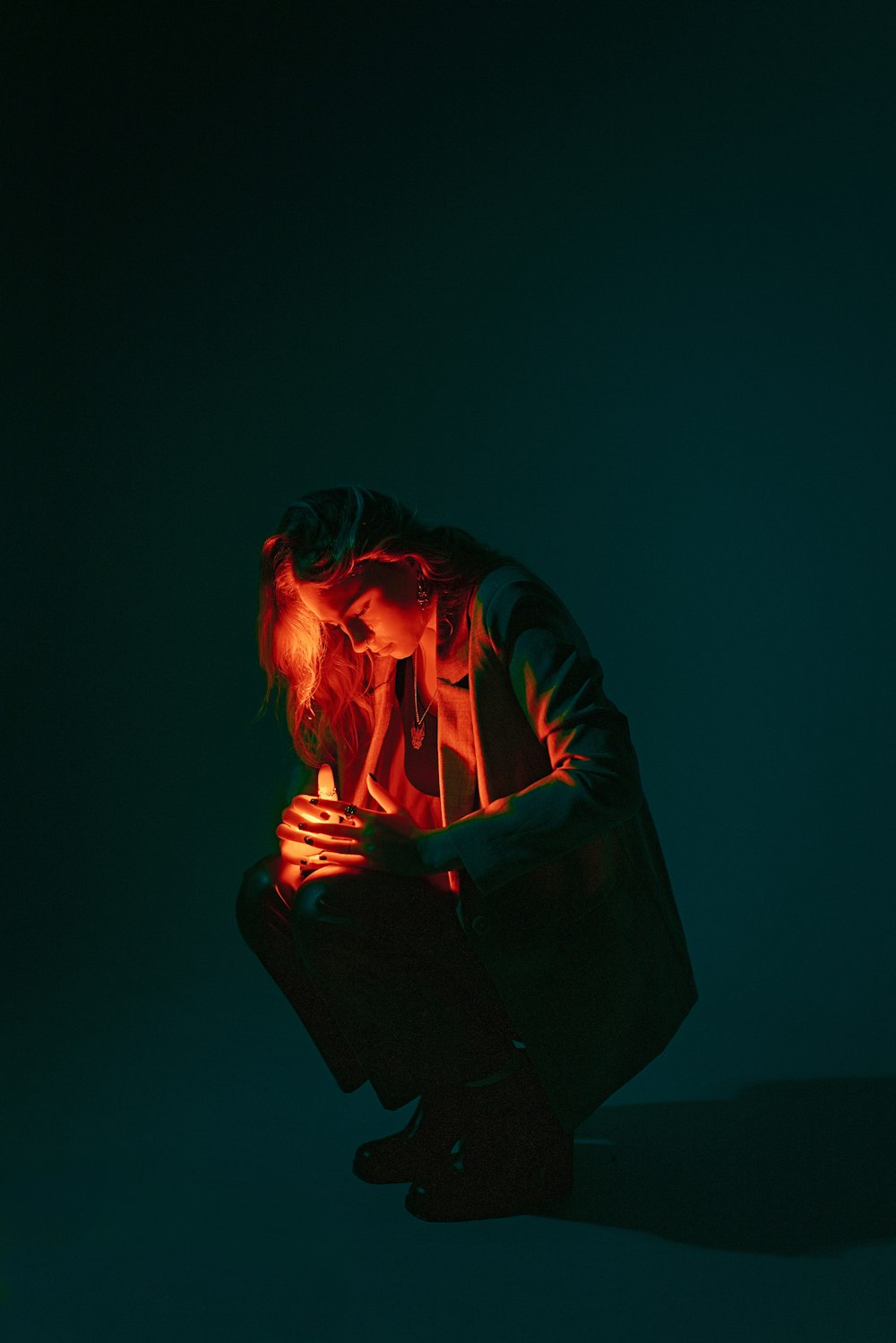 a man kneeling down in the dark with his hands on his knees