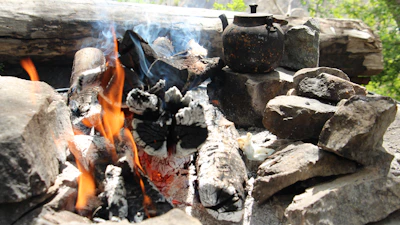 Campfire with glowing flames surrounded by historical props and weapons.