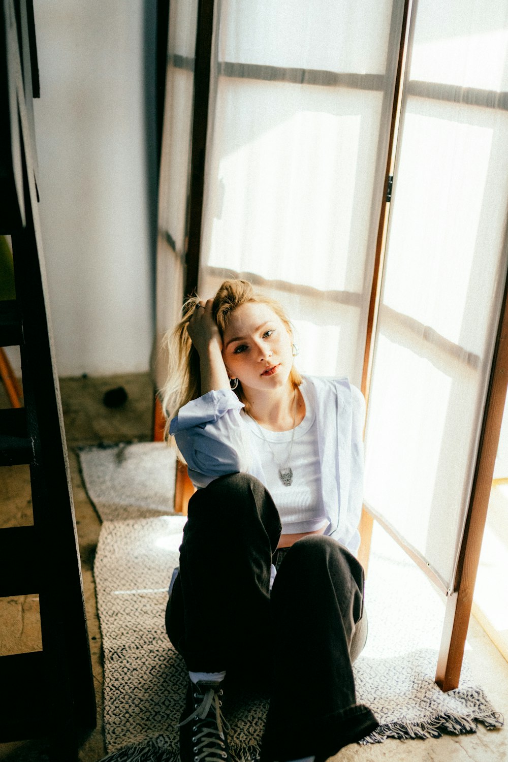 a woman sitting on the floor in front of a window