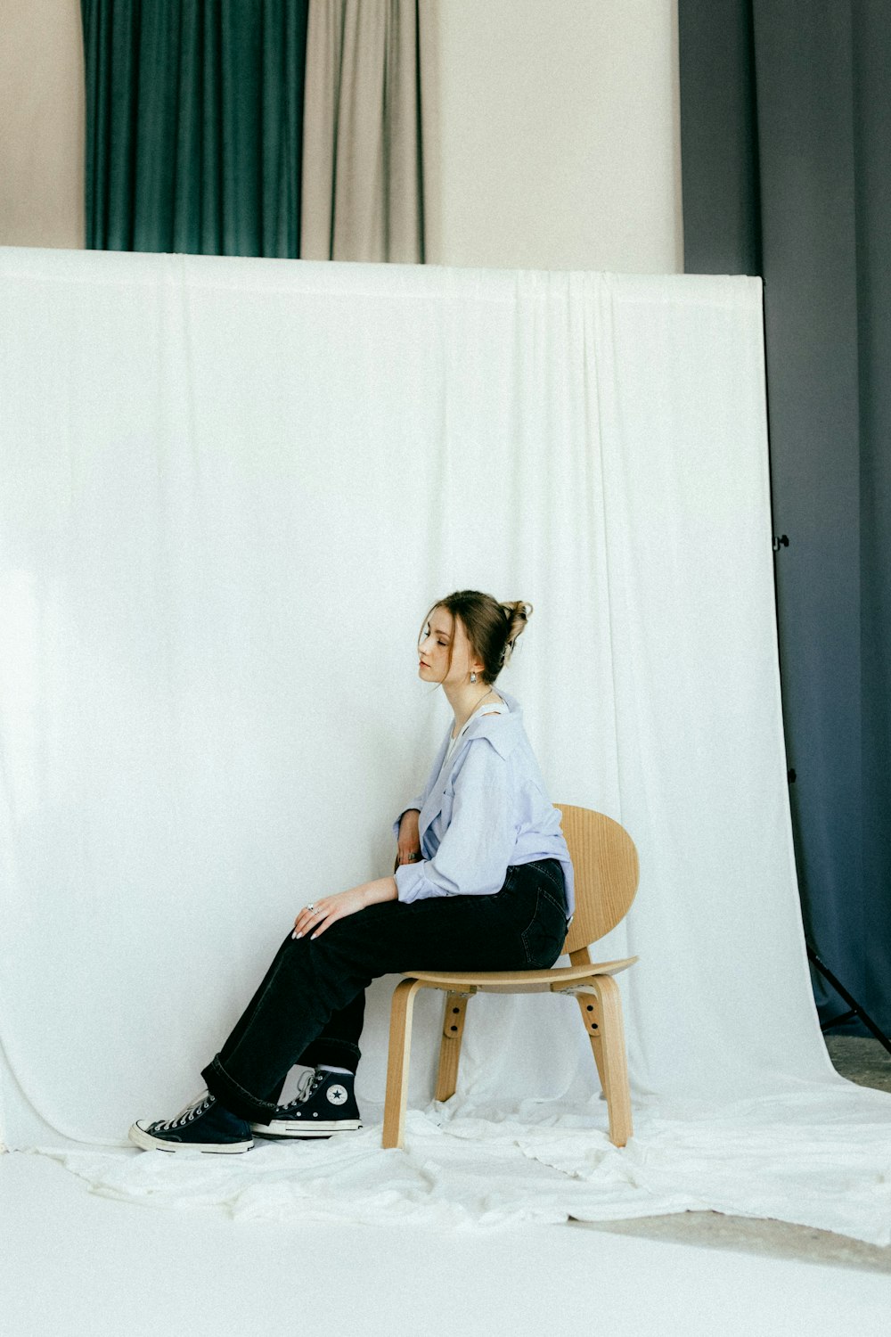 a woman sitting on a chair in front of a white backdrop