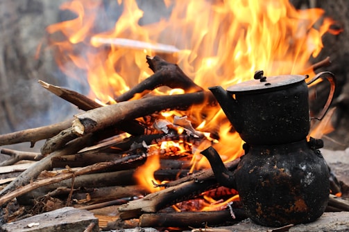 A vintage kettle steaming over an open flame.