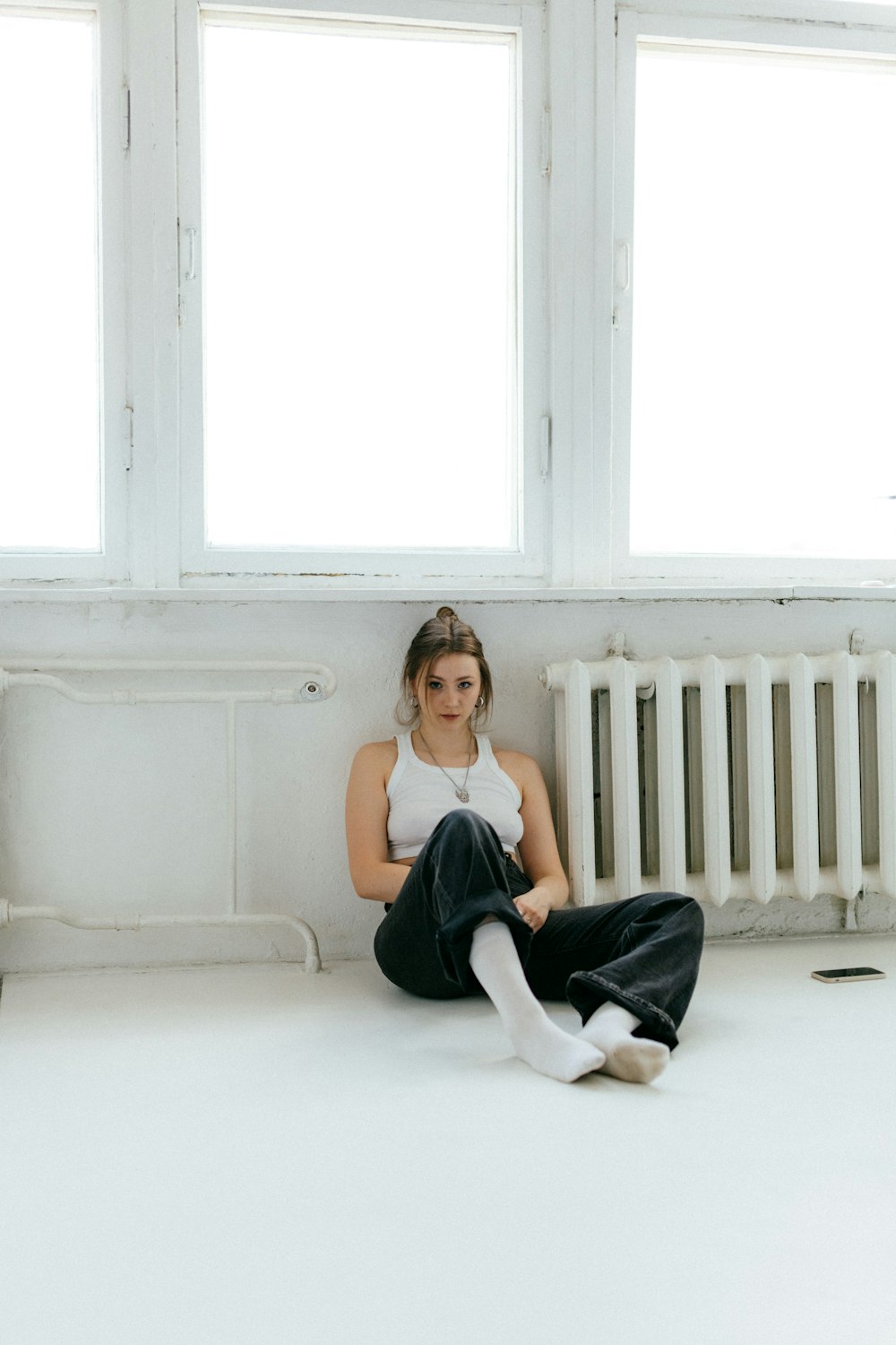 a woman sitting on the floor in front of a radiator