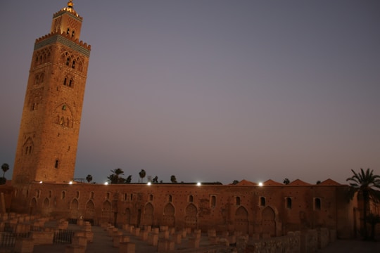 Two tall, elegant towers against a twilight sky, with gold-lit windows and traditional Emirati patterns subtly incorporated into the facade.