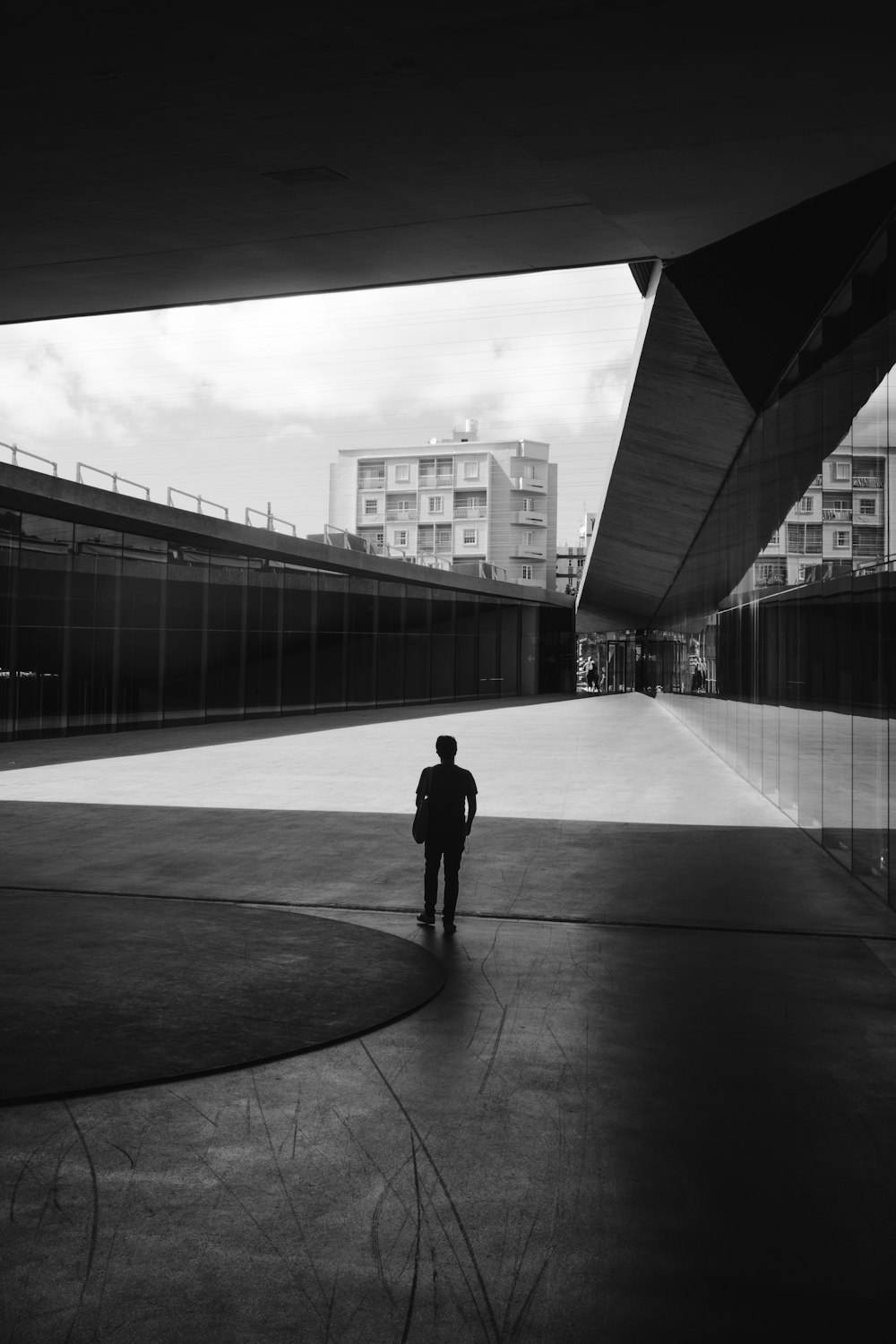 a black and white photo of a person standing in a courtyard