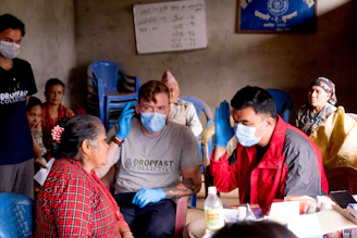 a group of people sitting around a table with masks on