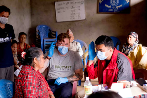 a group of people sitting around a table with masks on