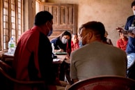 A group of people in a secret meeting, faces obscured, exchanging documents.