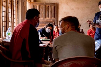 Community leaders gathered in a rustic meeting hall discussing social projects.
