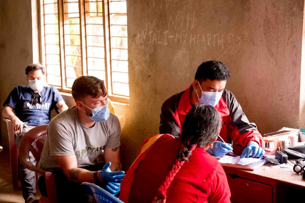 a group of people sitting around a table wearing masks