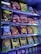 A vending machine filled with a variety of snacks and beverages, including bags of chips and packs of cookies and drinks. The packaging features bright colors and a mix of English and another script, likely Thai.