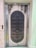 A metal elevator door designed to resemble a medieval vault door with rivets and decorative stone-like elements. The door features a symmetrical pattern and is set within a tiled wall with a small control panel displaying the floor number 711.