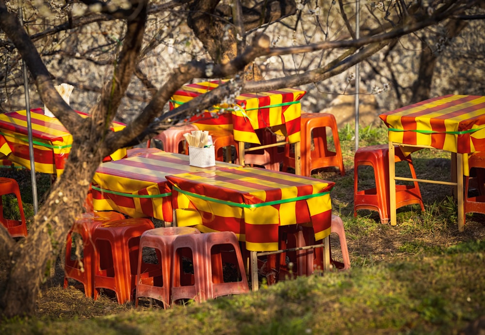 a bunch of colorful tables and chairs in the grass